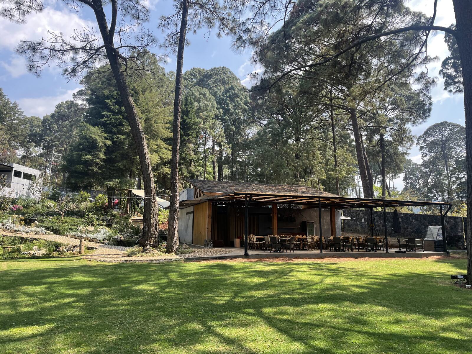 Pradera frente a un pabellón de madera entre pinos